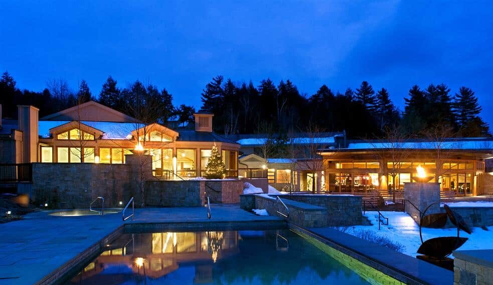 illuminated building at dusk with swimming pool reflection before it