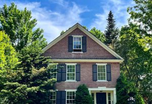 brick colonial with blue sky & trees